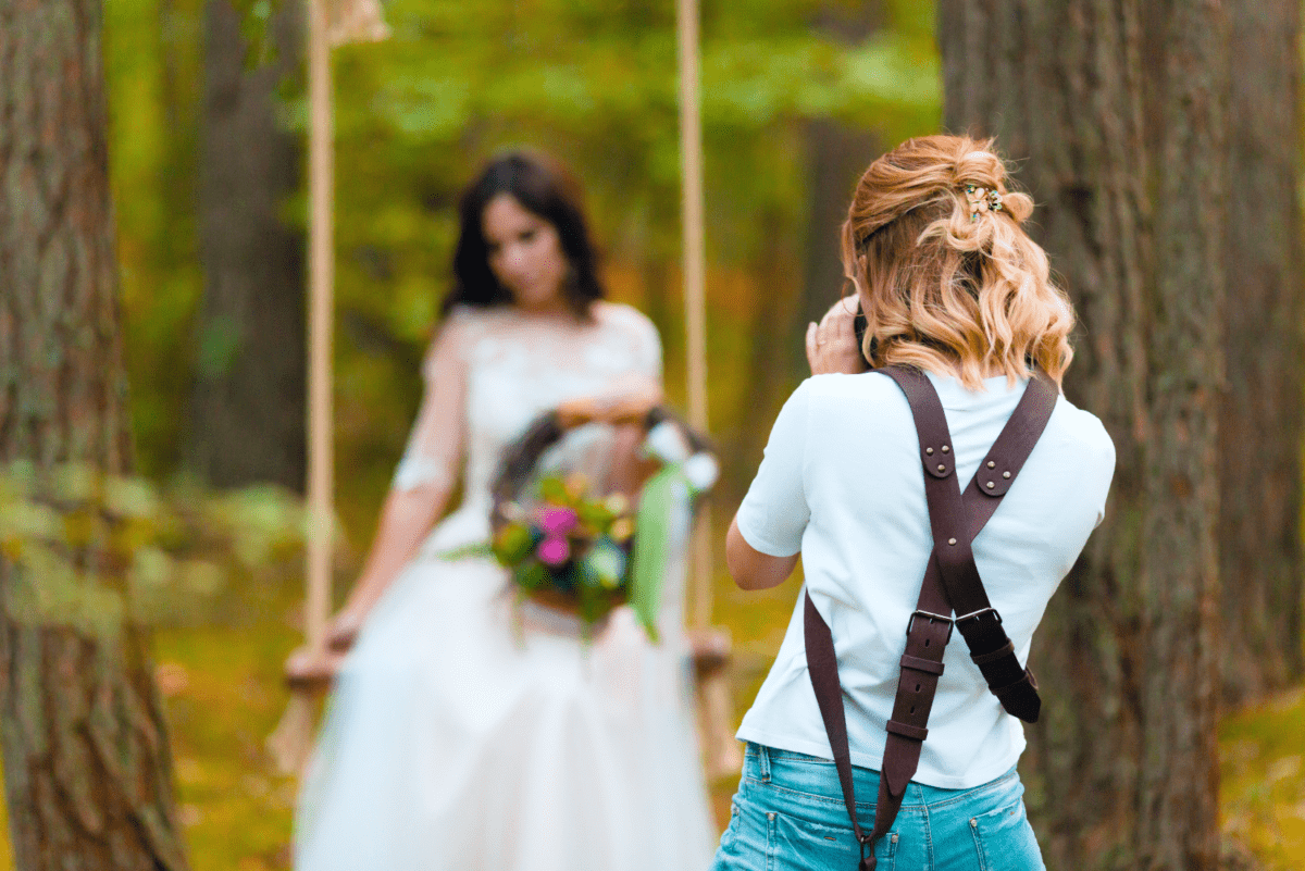 Wedding photographer photographing bride on swing